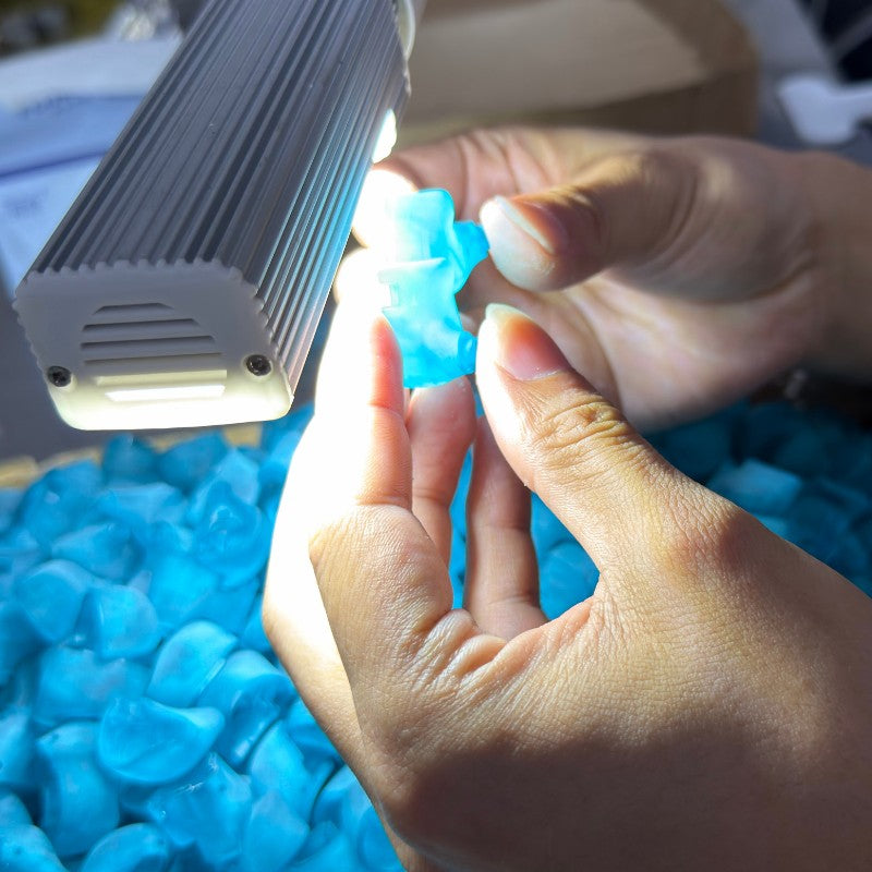 Person holding a blue object under a light source with a blurred background